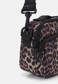 Bolso acolchado de estampado de leopardo en tonos marrón y negro, con herrajes negros, dos cremalleras y una correa ajustable. Forma rectangular compacta.