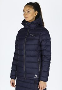 Navy puffer jacket featuring a zip closure, hood, and logo detailing. The material is smooth with horizontal quilted sections for insulation.