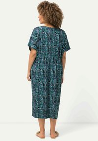 Maxikleid mit kurzen Ärmeln, ausgestattet mit einem mehrfarbigen Paisleymuster auf dunklem Hintergrund. Elastischer Bund, knielange Länge und entspannter Schnitt.