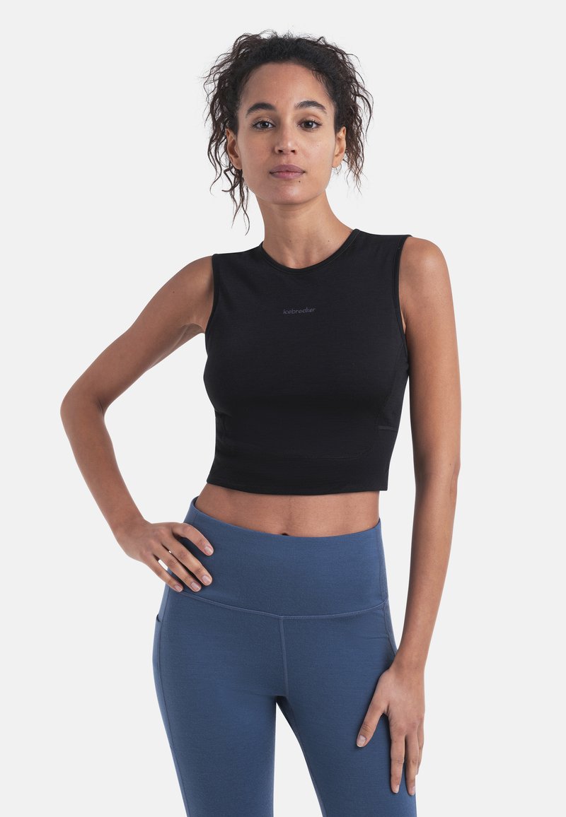 Musta urheilullinen crop-top, jossa on pyöreä kaula-aukko ja hihaton muotoilu. Yhdistetty korkeavyötäröisiin sinisiin leggingseihin. Sileä pinta, minimaalinen brändäys.