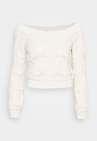 Suéter de punto de ganchillo sin hombros en color crema, con un patrón ondulado, puños acanalados y una silueta corta. Tejido suave y texturizado.