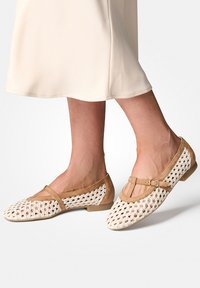 Ploché boty s hnědou koženou páskou a bílým vrchním dílem z otevřeného háčkování, s kulatou špičkou a nízkým podpatkem.