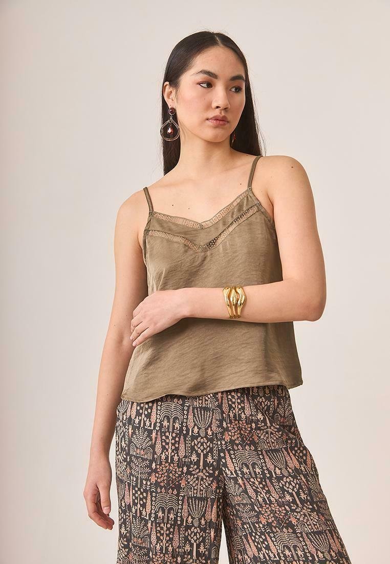 Top sin mangas de color verde oliva y ligero, con detalles de encaje. Combinado con pantalones de pierna ancha de tonos oscuros con diseños florales.