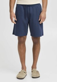 Shorts de sport bleu marine avec une taille élastique et un cordon de serrage, présentant une texture lisse et des poches latérales.