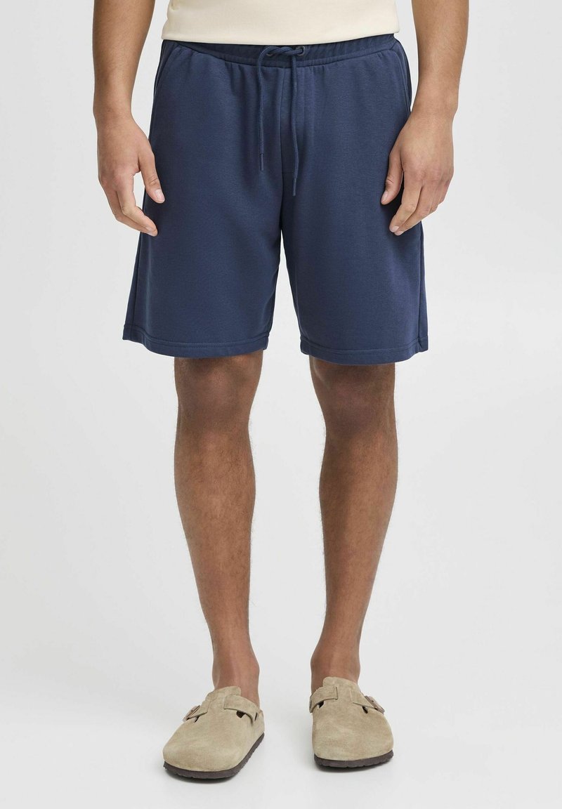 Shorts de sport bleu marine avec une taille élastique et un cordon de serrage, présentant une texture lisse et des poches latérales.