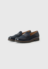 Mocassins en cuir bleu marine avec une finition brillante, présentant une large bande à l'avant, des semelles intérieures marron et des semelles en caoutchouc noir texturé.