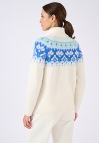 Pullover crema con colletto alto, decorato da un motivo geometrico blu e verde sulle spalle. Tessuto morbido e vestibilità morbida.
