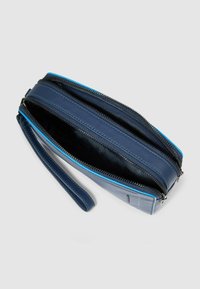 Portafoglio da polso in pelle blu con doppio scomparto con cerniera, texture liscia e cinturino sottile da polso. Interno con fodera nera a contrasto.