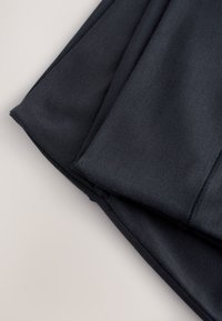 Foldet sort stof, der viser en glat tekstur og færdige sømme på en lys overflade.