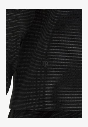 Czarna bluzka z tkaniny, z delikatnym wzorem w kropki, gładką strukturą i małym logo marki z przodu, na dole.