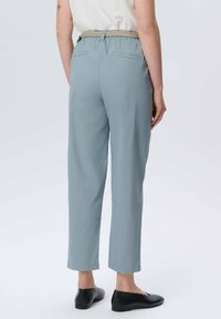 Jasnoniebieskie, luźne spodnie z elastycznym pasem i tkanym paskiem. Posiadają dwie tylne kieszenie i zwężane nogawki. Noszone czarne baleriny.