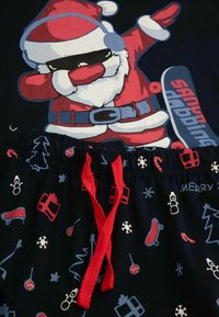 Krótki rękaw zestaw piżamowy z grafika Mikołaja w kolorach czerwonym i białym. Spodnie w kolorze granatowym z kolorowymi nadrukami w tematyce świątecznej; czerwony detal w postaci sznurka.