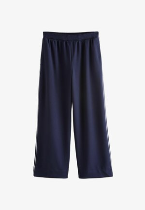 Sötétkék sportnadrág rugalmas derékpánttal, fehér oldalsávokkal és sima, könnyű szövettel.