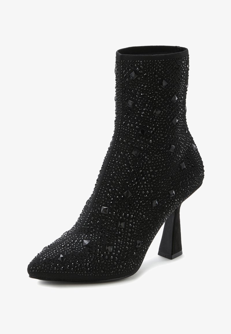 Botas de tobillo negras con punta afilada, adornadas con strass negros y tachuelas cuadradas, con un upper de tela texturizada y un tacón cuadrado.