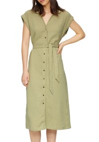 Kostium w kolorze oliwkowym, z guzikami z przodu, wykonany z teksturowanej tkaniny, z paskiem w talii i krótkimi, luźnymi rękawami. Posiada drewniane guziki na całej długości przodu.