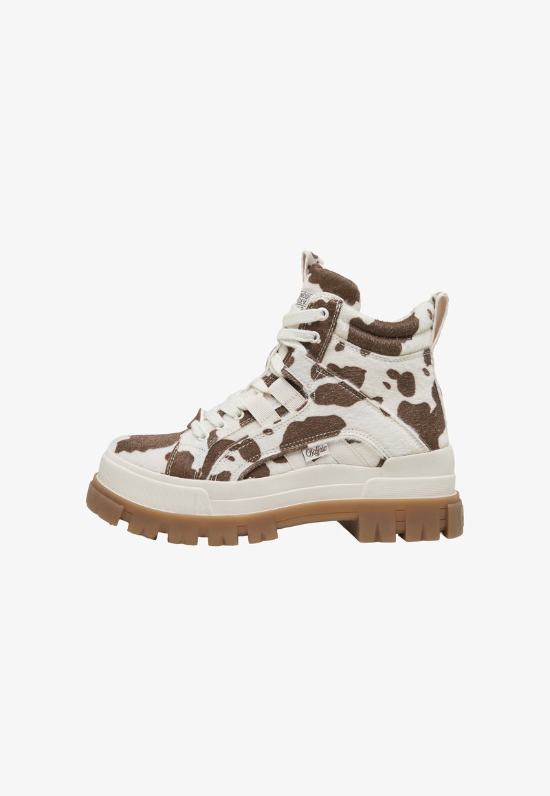 Αθλητικό παπούτσι τύπου high-top με καφέ και λευκό μοτίβο αγελάδας, χοντρή μπεζ σόλα, λευκά κορδόνια και υφασμάτινη θηλιά στο πίσω μέρος.