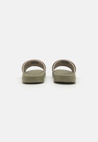 Grønne gummisandaler med flat såle, åpen bak, og avrundede overtråder. Enkelt design, minimalistisk estetikk, passende for daglig bruk.