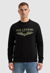 Černá mikina vyrobena z bavlny s kulatým výstřihem, s zlatým textem "PME LEGEND AMERICAN CLASSIC" a grafikou křídel na přední straně.