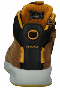 Sneaker in pelle marrone e tessuto nero con dettagli gialli, dotato di un colletto imbottito e una suola in gomma bianca. Marchio Geox sul tallone.