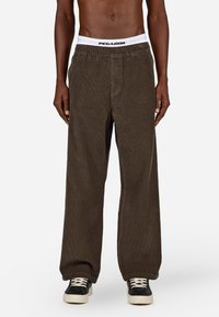 Brūnas korduroja bikses ar vaļīgu piegriezumu, ar baltu jostasvietu un "PEGADOR" logotipu. Svītraina tekstūra un vienkāršs dizains ar sānu kabatām.