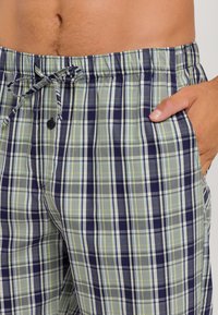 Geruite shorts met een mix van groen, marineblauw en lichtblauw. Gemaakt van lichtgewicht stof met een elastische band en zijzakken.