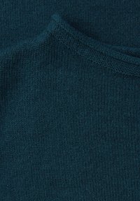 Ciemnoturkusowa dzianina o gładkiej fakturze. Charakteryzuje się delikatnym prążkowaniem i subtelnym połyskiem, co wskazuje na miękkość i ciepło.