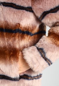 Płaszcz z futerka ekologicznego w kolorze różowym z brązowymi i granatowymi paskami. Miękka faktura, długie rękawy oraz wsuwana kieszeń po boku.