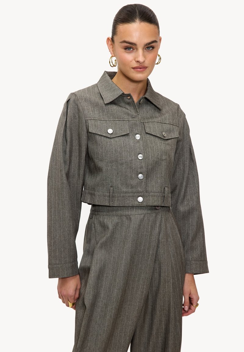 Veste en jean grise à rayures, coupée, avec fermeture par boutons, poches à rabat et col classique. Dispose de manches longues et d'une coupe ajustée.