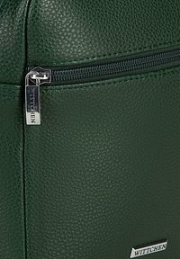 Borsa in pelle verde con superficie testurizzata, zipper nera e un'incorniciatura in argento con il nome del marchio "Wittchen" esposto.