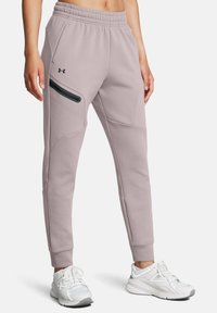 Hellegraue Jogginghose mit schlankem Design, elastischem Bund, schmal zulaufenden Beinen, seitlichem Reißverschlussfach und dezentem Logo-Detail auf der Vorderseite.