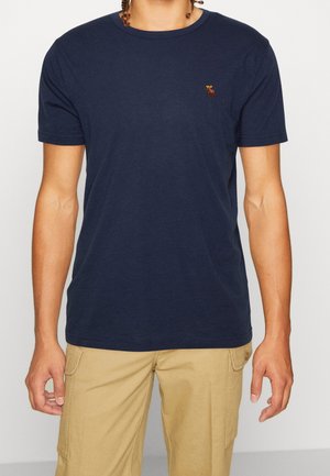 Marineblaues T-Shirt aus Baumwolle mit Rundhalsausschnitt und kurzen Ärmeln, versehen mit einem kleinen gestickten Detail auf der linken Brust.