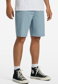 Light blue shorts with a classic cut and smooth texture. Paired with black high-top sneakers and white crew socks.