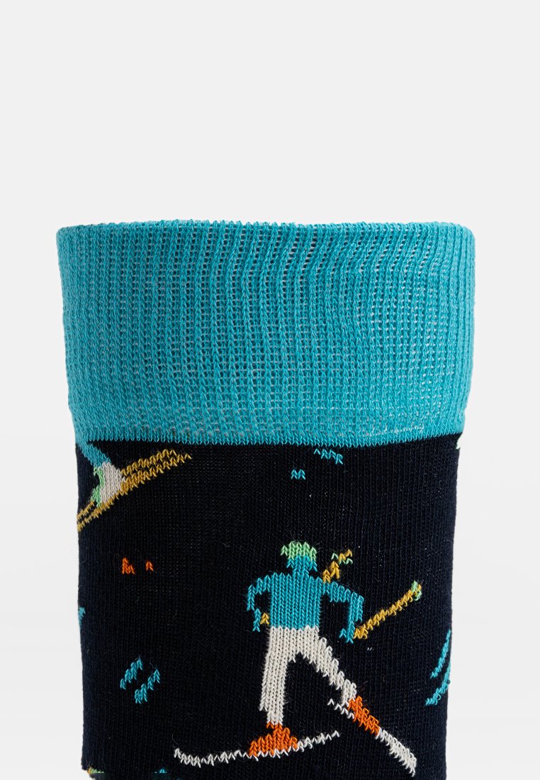 Marineblaue Socke mit einem türkisfarbenen Bund, der bunte Skifahrerfiguren in einem gestickten Muster zeigt, mit unterschiedlichen Texturen im gesamten Design.