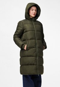 Casaco puffer verde oliva com capuz, apresentando um fecho de correr completo, costura horizontal larga e bolsos laterais. Textura suave e mate.