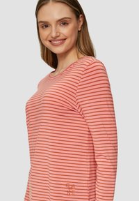 Rood en roze gestreepte lang-sleeve t-shirt gemaakt van zachte stof. Beschikt over een ronde halslijn en een klein merkembleem rechtsonder.