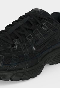 Schwarzer Nike-Laufschuh mit Mesh-Gewebe, strukturierter Sohle und detailliertem Schnürsystem, zeigt seitliches Logo und obere Gestaltungselemente.