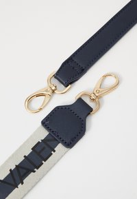 Sangle navy avec une finition texturée, dotée de quincaillerie dorée, de fermoirs en forme de homard, et d'une section en tissu gris avec le logo "Valentino".