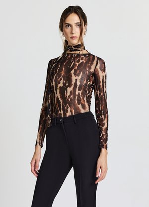 Haut transparent à manches longues avec un motif animal en marron et noir. Le design col roulé complète le pantalon noir ajusté.