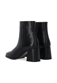 Czarne skórzane botki za kostkę o gładkiej fakturze, średniej wysokości obcasie słupkowym oraz z detalem w postaci bocznego zamka. Elegancka i dopasowana sylwetka.