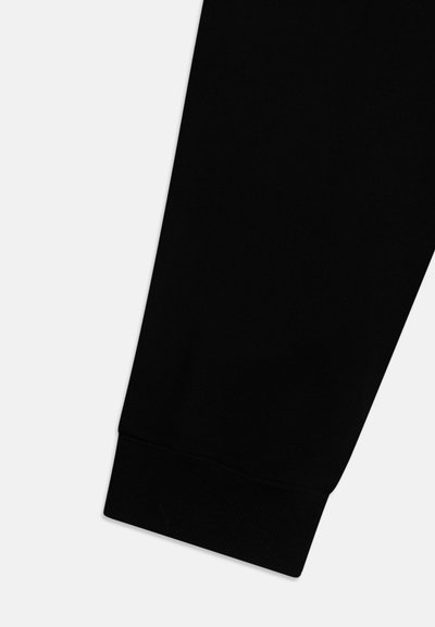 Svart bomulls joggebukse med ribbestrikket mansjett ved ankelen og en jevn tekstur gjennom hele. Enkelt, rent design uten synlige mønstre.