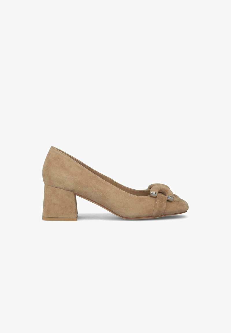 Escarpin beige en daim à talon carré avec un bout rond et une sangle décorative ornée de quincaillerie argentée sur le devant. Texture douce.