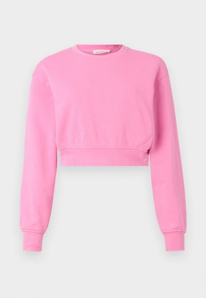 Roza skrajšani pulover z dolgimi rokavi, okroglim izrezom in rebrastimi manšetami. Narejen iz mešanice mehkega bombaža z gladko teksturo.