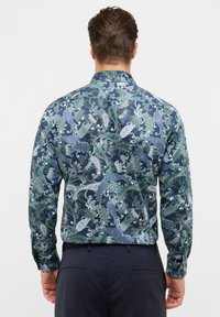 Langarmshirt met een donkerblauwe basis en complexe groene en witte paisleypatronen, met een geknoopte kraag en een getailleerde pasvorm.