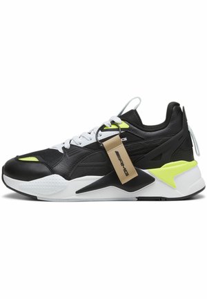 Zapatilla en blanco y negro con un acabado texturizado, acentos en verde neón y una suela blanca. Incluye una etiqueta unida a los cordones.