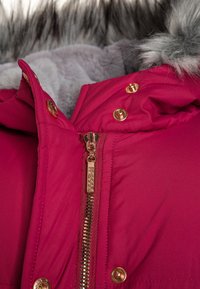 Fuchsia polstret jakke med hætte forede med faux pels, metalgul hardware, lynlås lukning foran og trykknapper langs pladen.