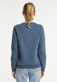 Sudadera azul de manga larga, con tejido texturizado, puños y dobladillo acanalados, que presenta un parche cuadrado en la parte posterior y un pequeño acento de logo.