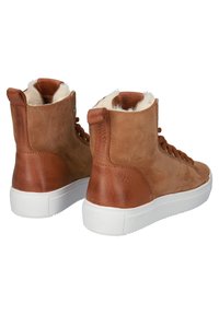 Ruske nahke škornje do gležnja z umetnim krznom, belim gumijastim podplatom in vezalnim dizajnom; značilne so različne teksture in gladki detajli.