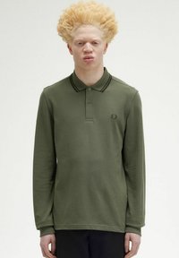 Polo a maniche lunghe di colore verde oliva, realizzato in tessuto morbido, con patta a due bottoni e colletto a righe nere. Piccolo logo sul petto.