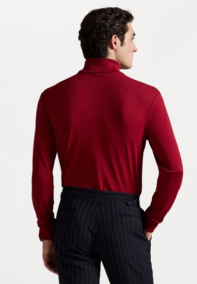 Burgundská rolák s dlhým rukávom, hladká textúra. V kombinácii s tmavomodrými nohavicami s prúžkami, obsahujúcimi bočné vrecká a zadný detail.