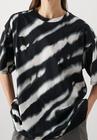 Camiseta de gran tamaño en blanco y negro con estampado tie-dye, cuello redondo, mangas cortas y un ajuste relajado, con una textura de algodón suave.